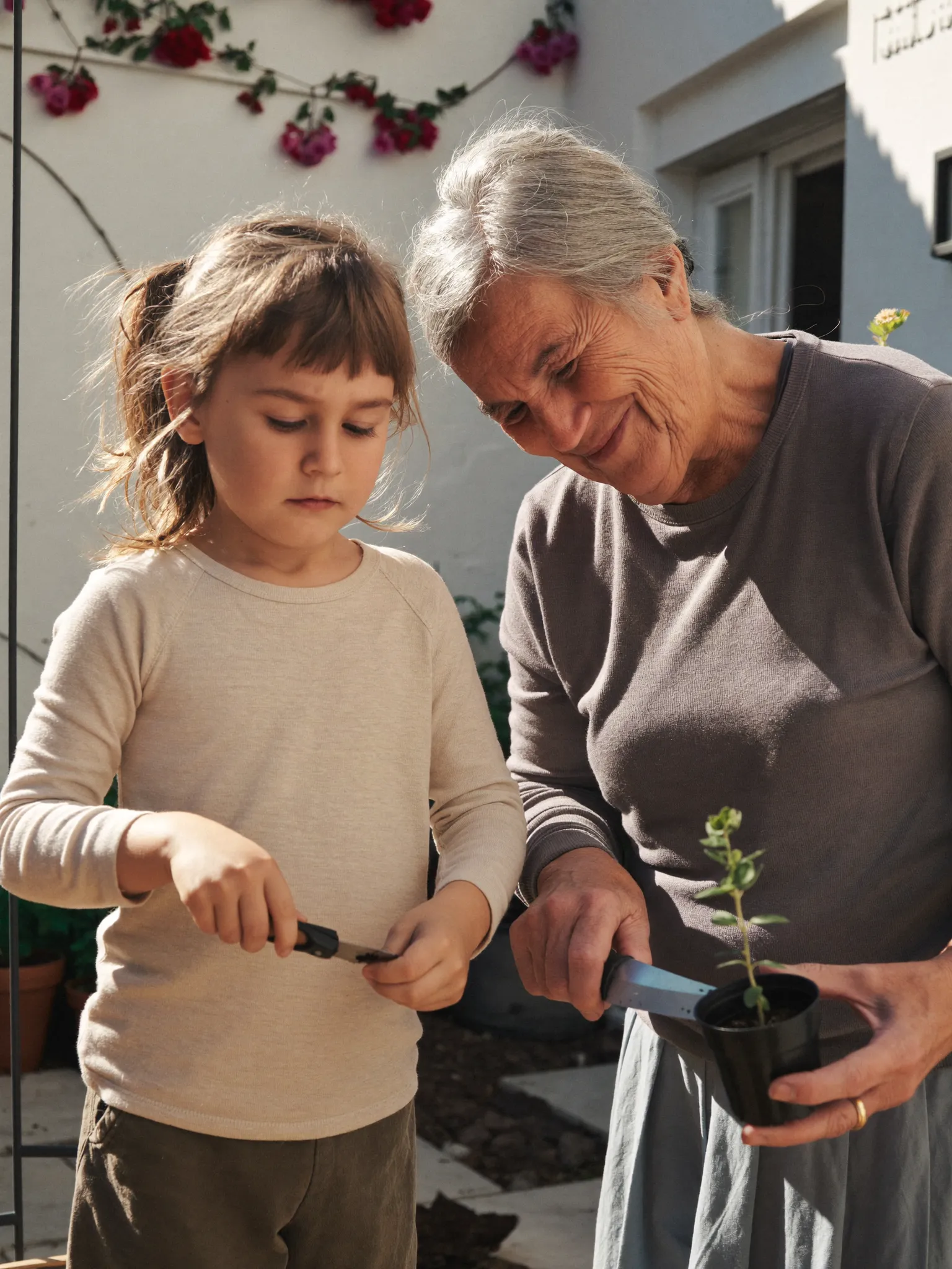 Elena handing a plant cutting to her grandchild in Athens