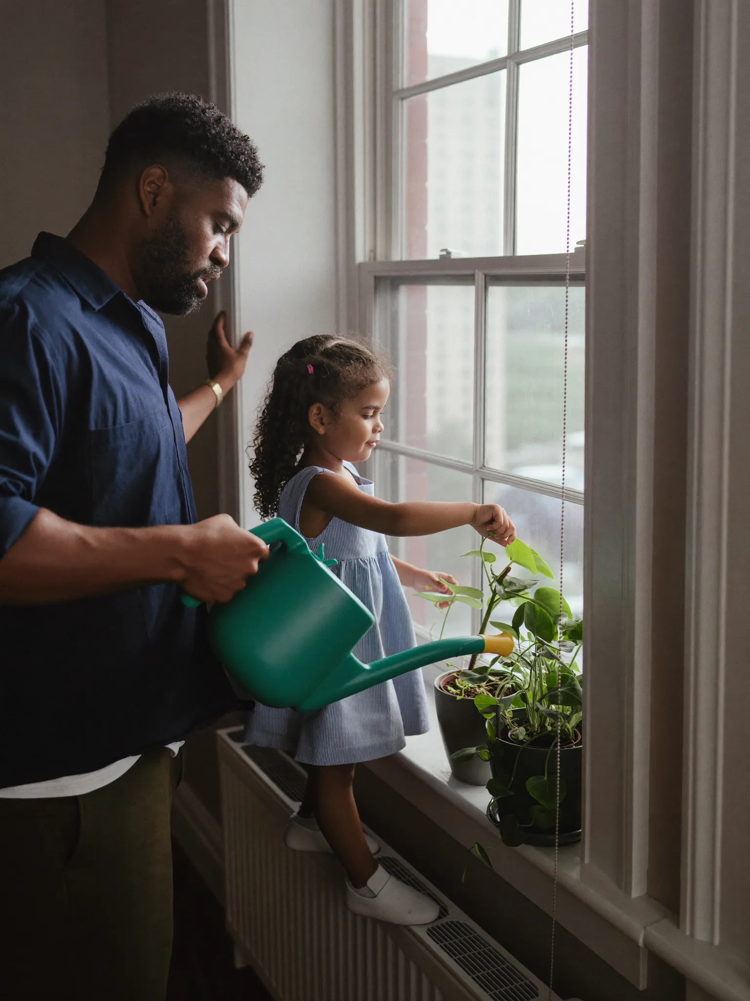 Tom watering plants with his young daughter in Toronto