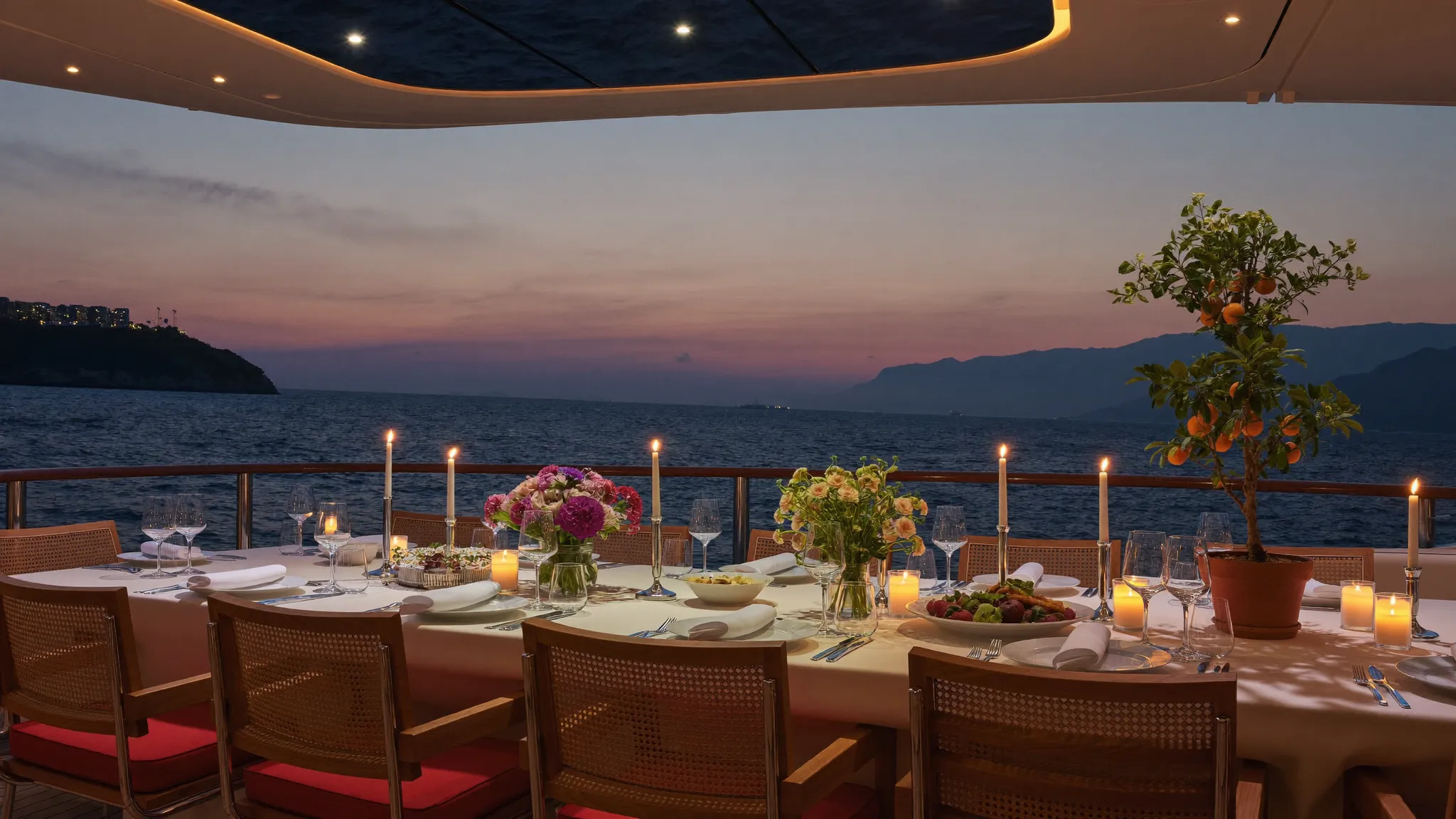 Superyacht aft-deck dinner table at dusk with a potted kumquat centerpiece