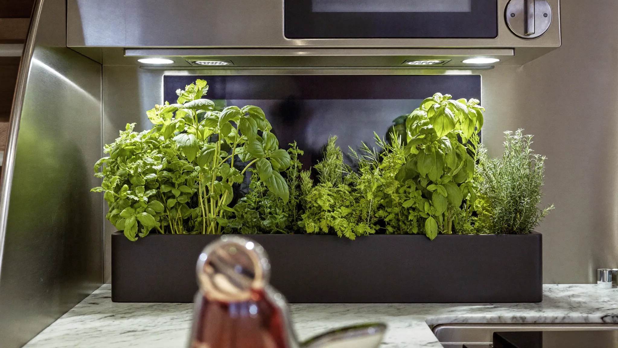 A built-in hydroponic herb garden with basil, rosemary and thyme in a superyacht galley